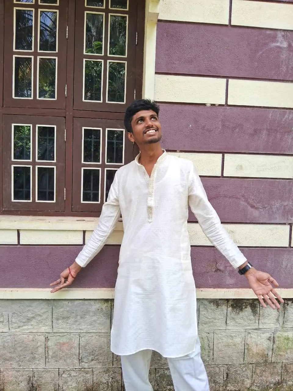 Srujan in a white kurta outside a village house
